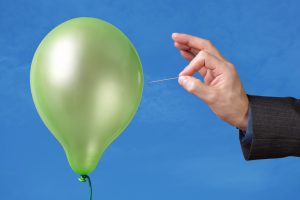 A pin being used to pop a green balloon
